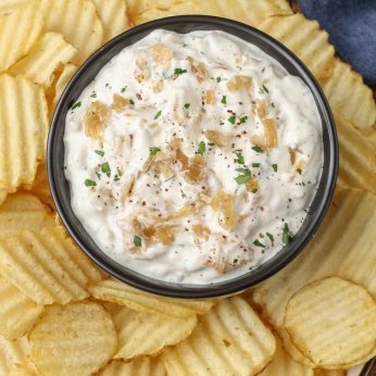 potato chips surrounding bowl of dip on wooden table