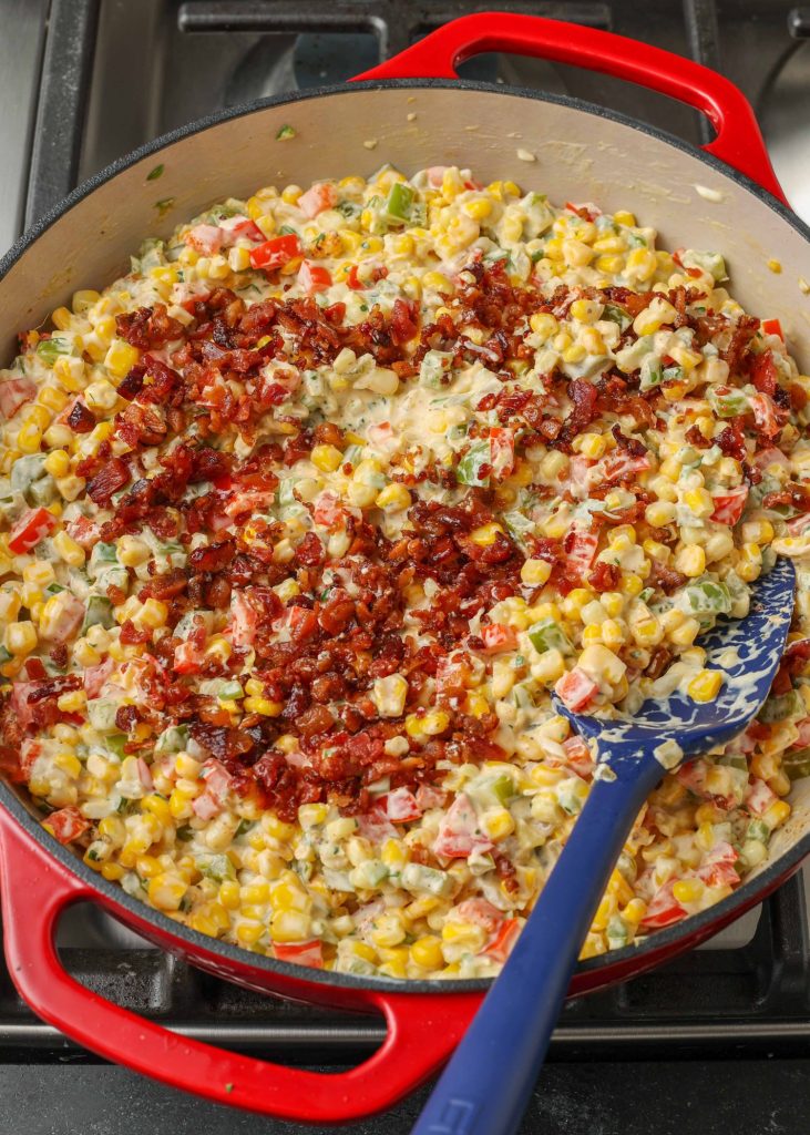 Overhead shot of corn dip midway through the cooking process, topped with crumbled bacon