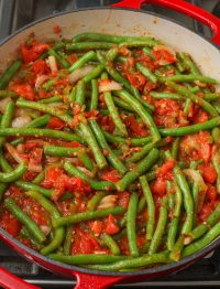 saucy green beans with tomatoes in enameled skillet