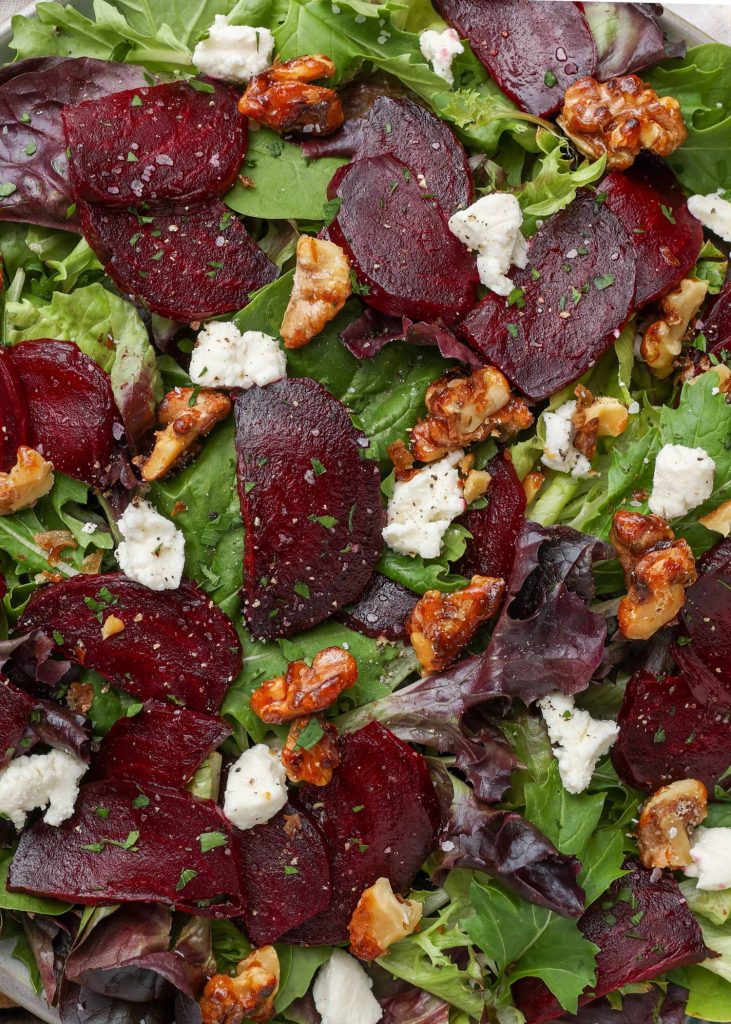 a close up shot of the roasted sliced beets and goat cheese and candied walnuts