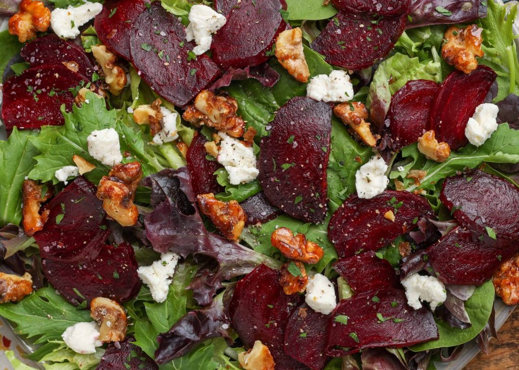 a horizontally aligned close up shot of the roasted sliced beets and goat cheese and candied walnuts