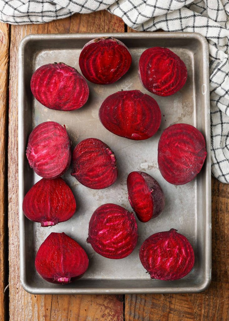 raw beets have been sliced and placed on a metal sheet pan