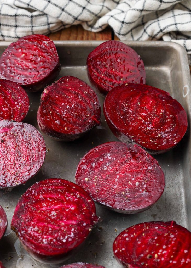 a close up of the seasoning on sliced beets on a metal pan