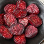 a close up image of glorious roasted beets on a black plate