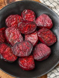 a close up image of glorious roasted beets on a black plate