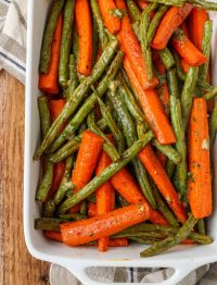 Overhead vertical shot of roasted carrots and green beans in a long white tray