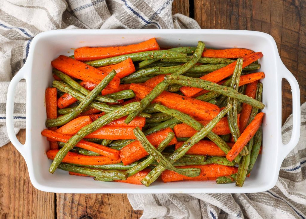Horizontal shot of roasted carrots and green beans in a long white tray