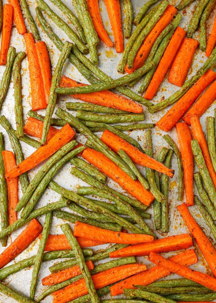 Roasted carrots and green beans on a baking sheet