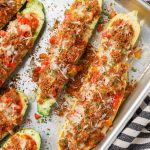 Overhead shot of zucchini stuffed with sausage, bell peppers, and cheese in a long sheet pan