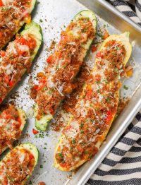Overhead shot of zucchini stuffed with sausage, bell peppers, and cheese in a long sheet pan