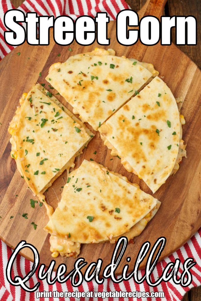 Overhead shot of quartered cheesy corn quesadilla, served on a round wooden cutting board on a striped red and white hand towel