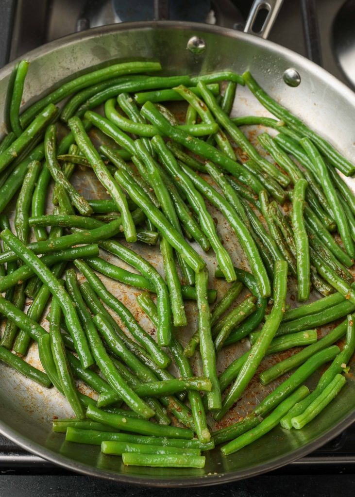 Fresh green beans just beginning to cook in a stainless steel skillet