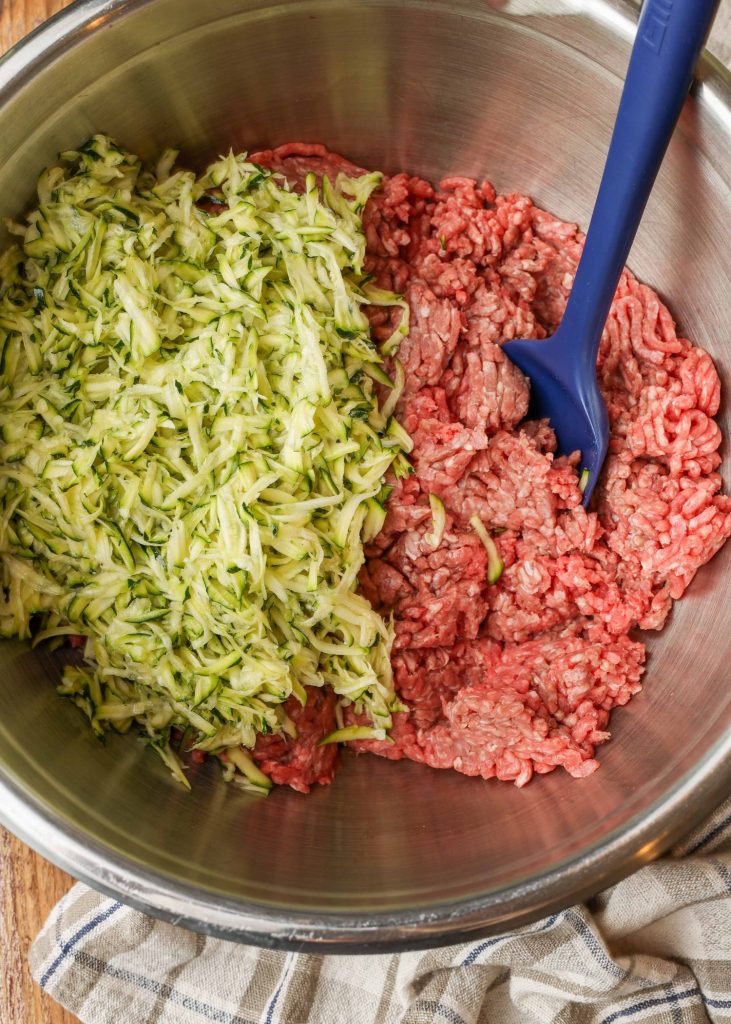 shredded zucchini and ground beef in mixing bowl