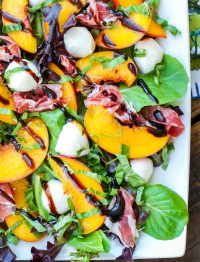 balsamic glaze over caprese salad made with peaches on white platter