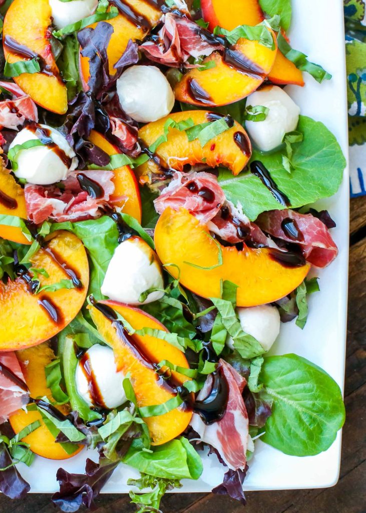 balsamic glaze over caprese salad made with peaches on white platter