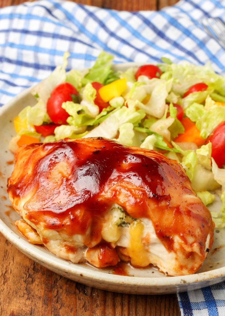 A stuffed chicken breast on a plate with a side salad.