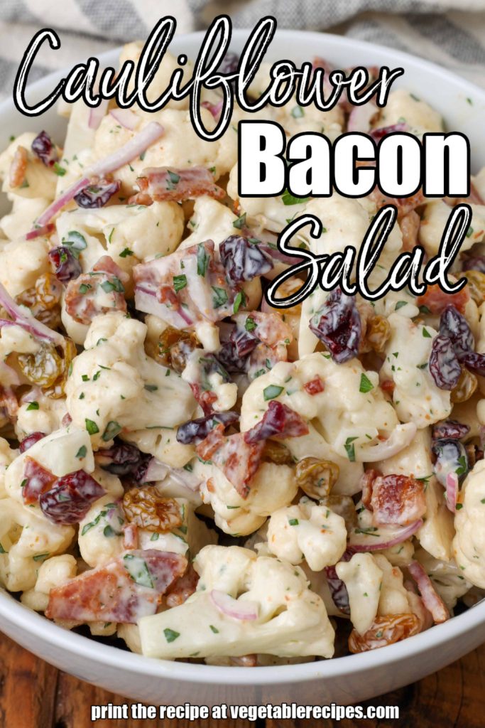 white lettering has been overlaid this image of a salad in a white bowl on a wooden tabletop. it reads, "Cauliflower Bacon Salad."