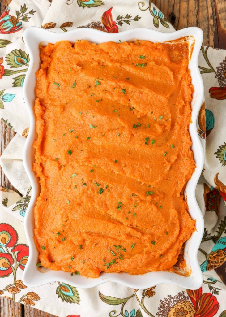 A vertically aligned photo of a white baking dish, loaded with ground beef casserole topped with mashed sweet potatoes.