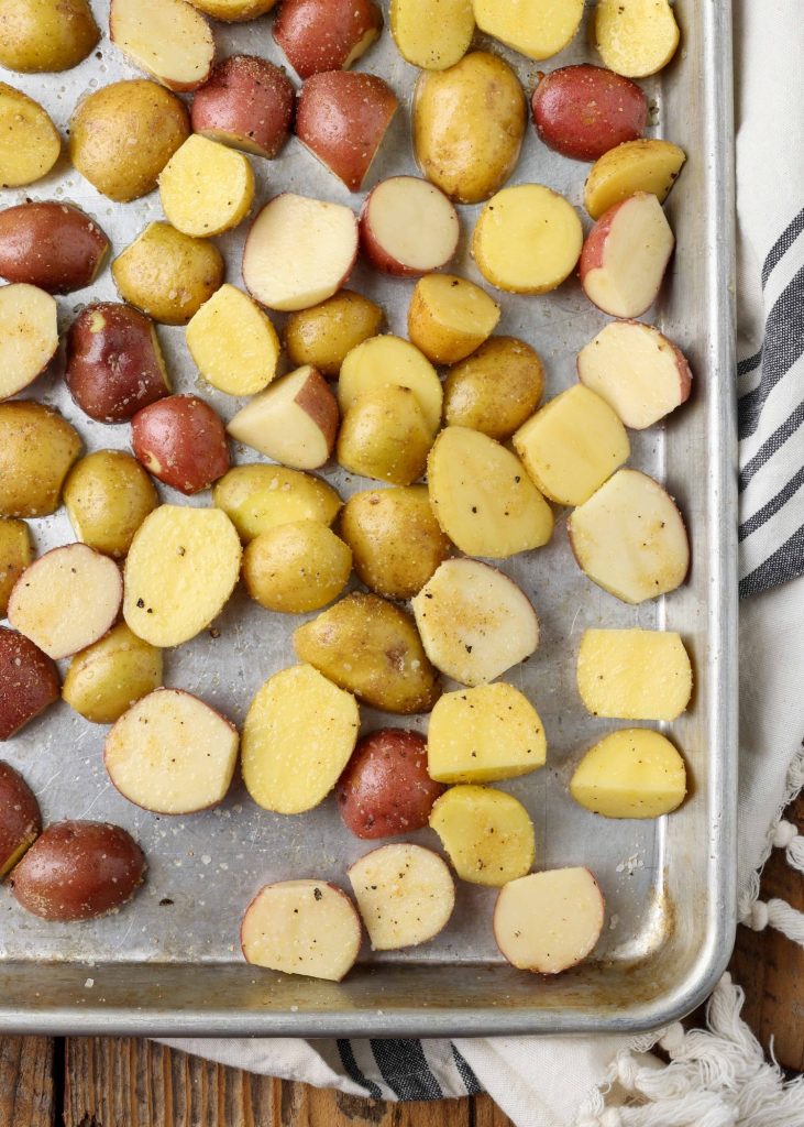 Potatoes sprinkled with spices and drizzled with olive oil are ready to go into the oven.