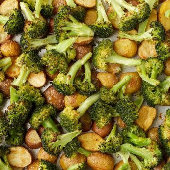 A vertically aligned, close up shot of broccoli and potatoes, fresh from the oven.
