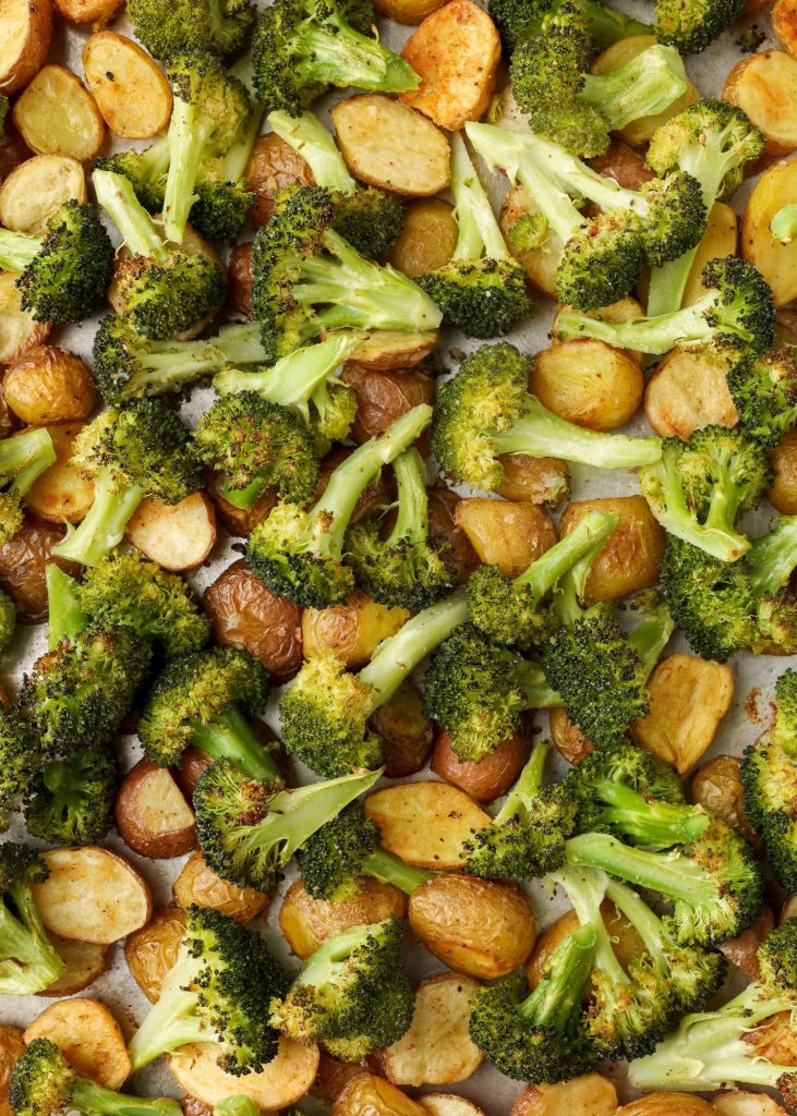 A vertically aligned, close up shot of broccoli and potatoes, fresh from the oven.