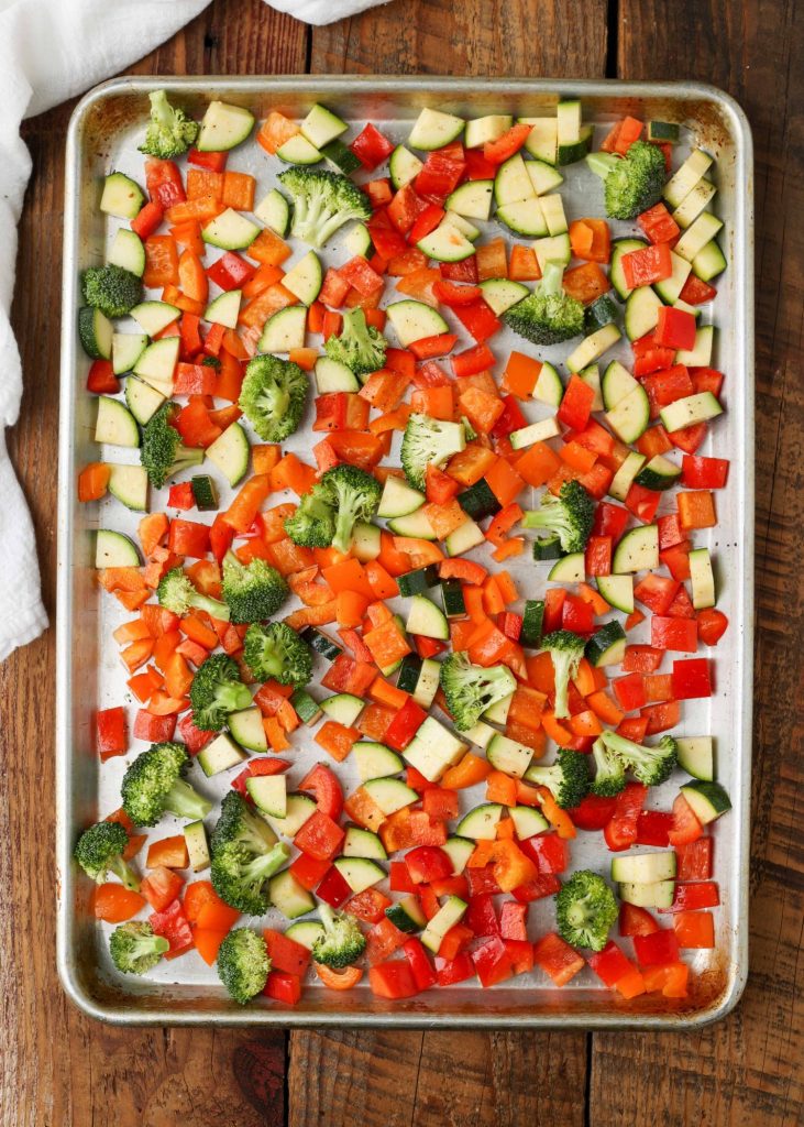 The vegetables have been mixed together with oil and salt and pepper on this metal sheet pan, ready to go into the oven.