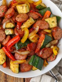 a top down photo of a bowl of sausage zucchini skillet on a wooden tabletop.