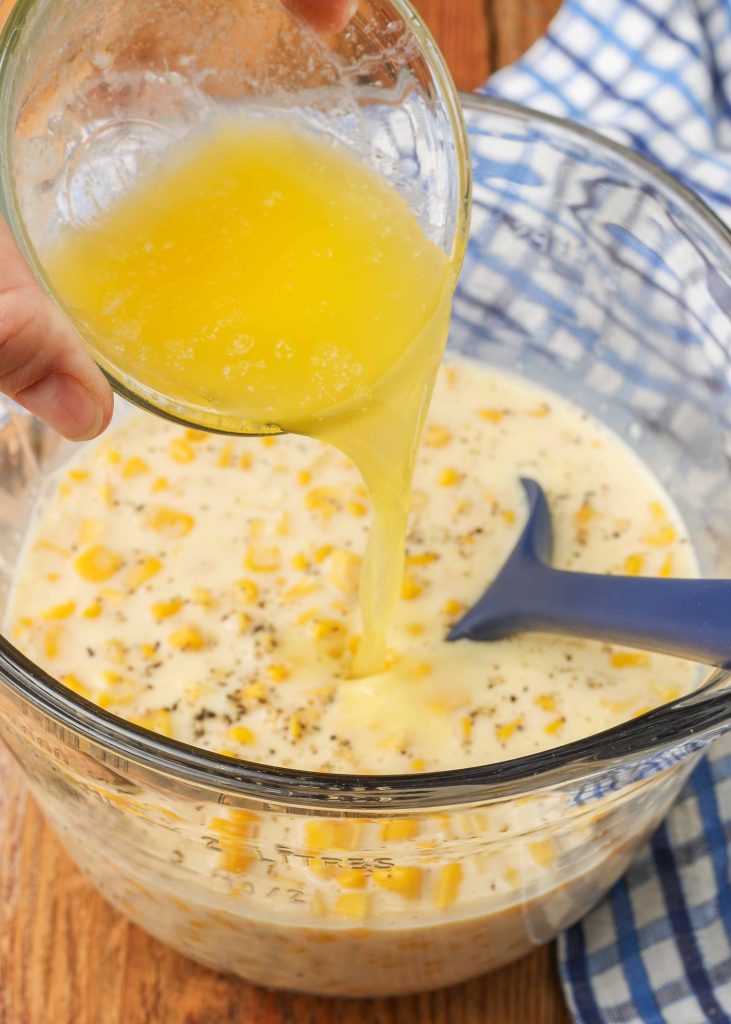 Pouring melted butter onto the milk and corn in the mixing bowl