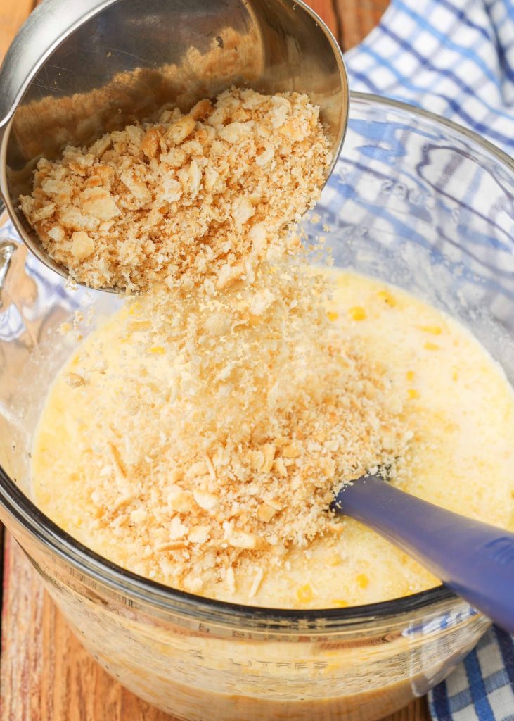 sprinkling ritz cracker crumbs onto the mixed up milk, butter, and corn in a mixing bowl.