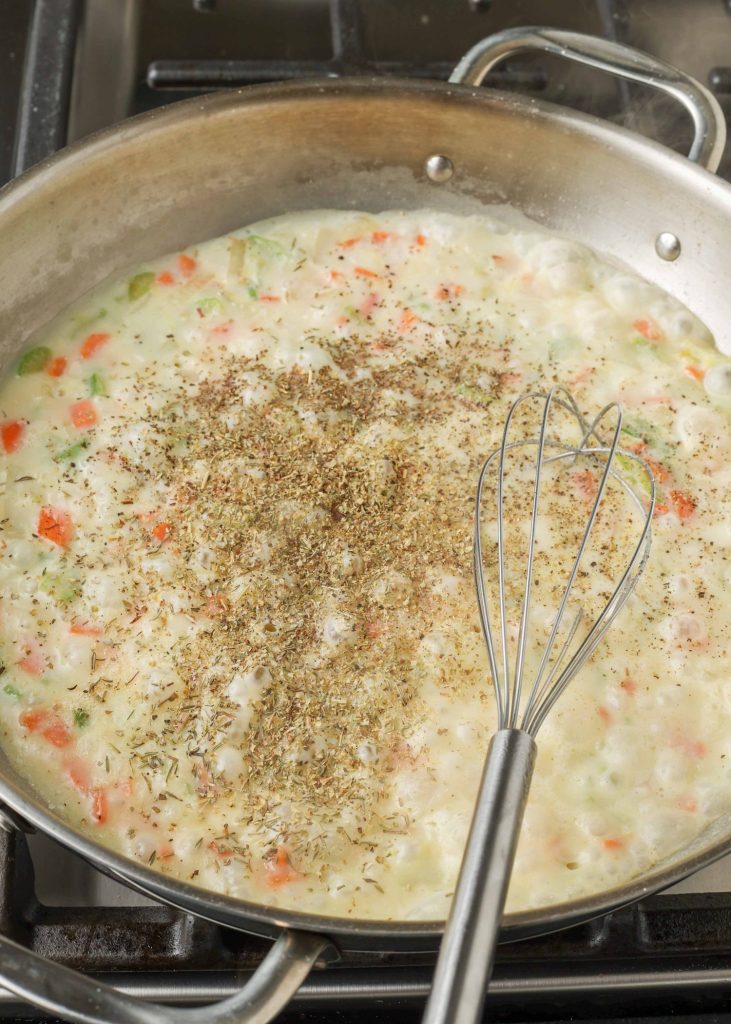 cream sauce with spices in skillet with whisk