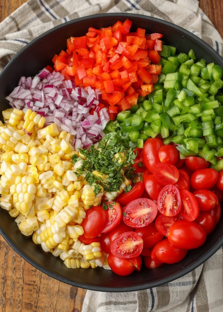 All of the ingredients for this corn salad have been arrayed in a bowl together, prior to mixing.
