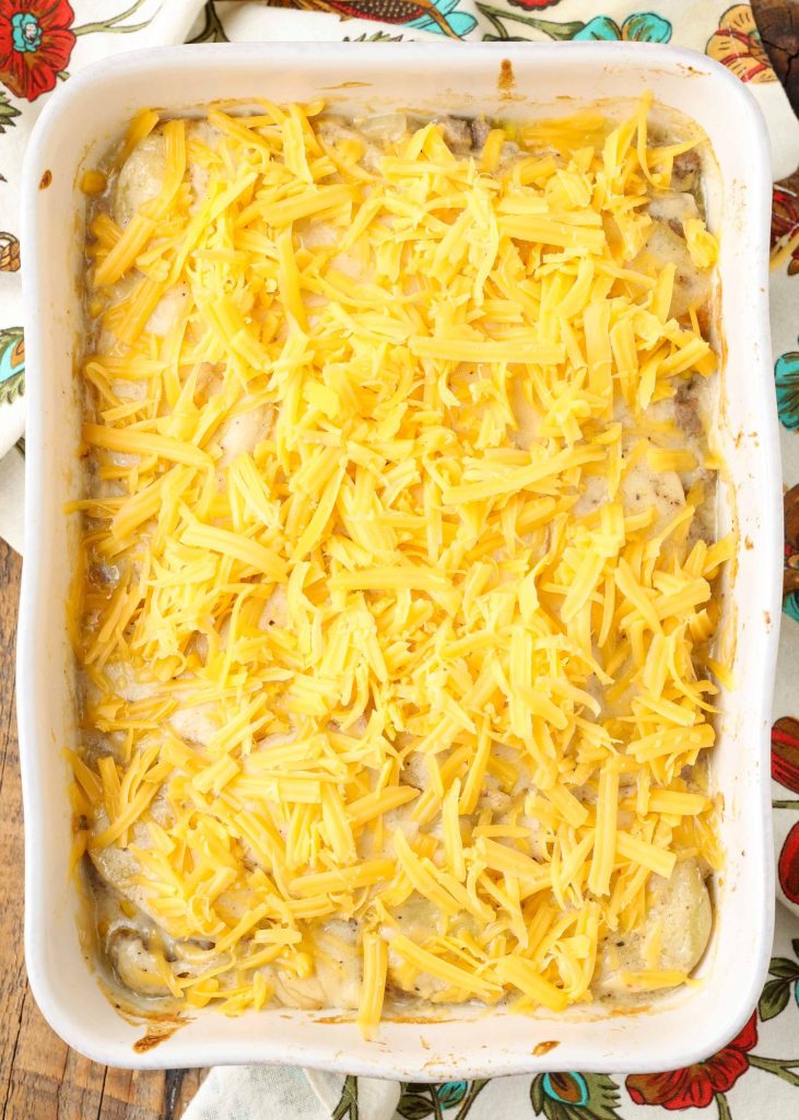 Overhead vertical shot of cheesy ground beef potato casserole in a long white tray just prior to cooking; the cheese has not yet been melted