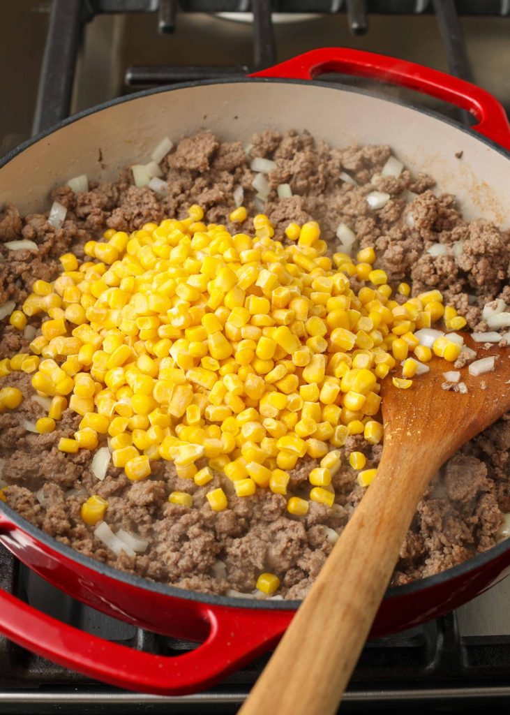 Ground beef, onions, and corn in a saucepan