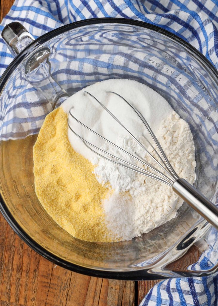 All of the dry ingredients have been placed in a clear glass mixing bowl with a whisk in this top down photo.