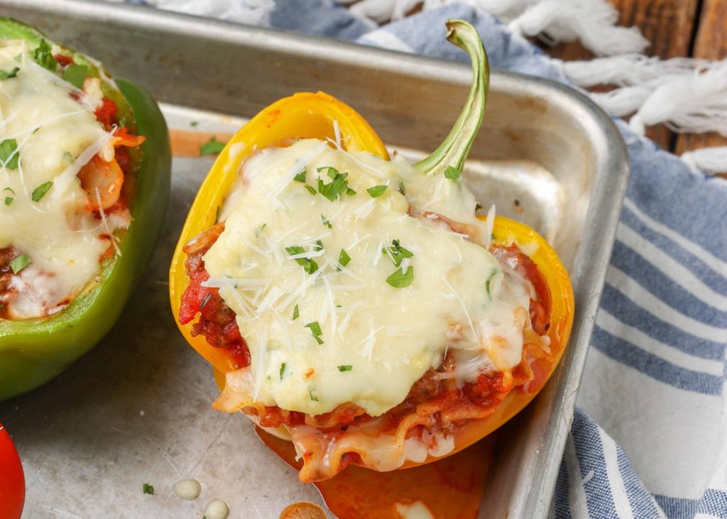 A stuffed pepper with a cheesy topping is visible on a metal baking sheet in this horizontally aligned photo.