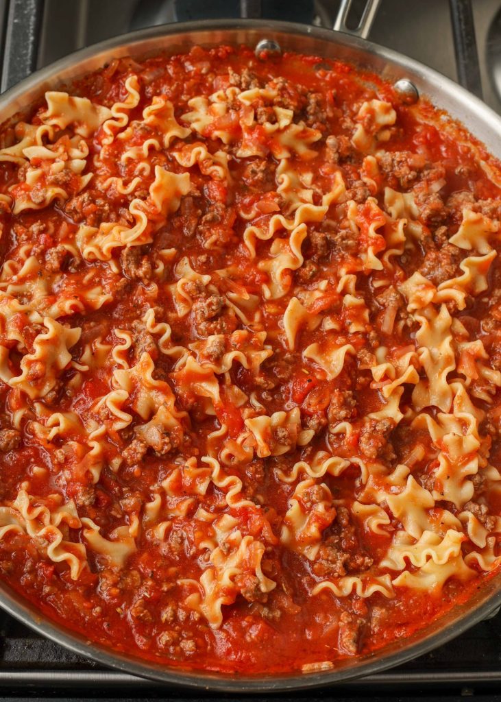 Pasta and meat sauce are mixed together in a pan.