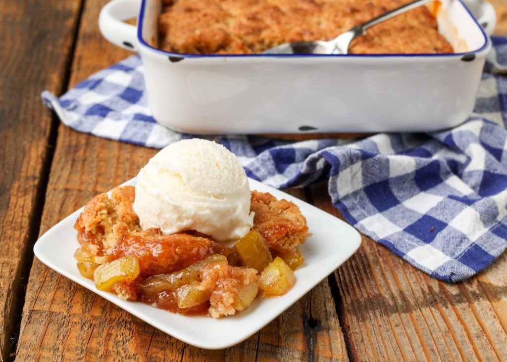 square white plate holding cobbler with a scoop of ice cream on top