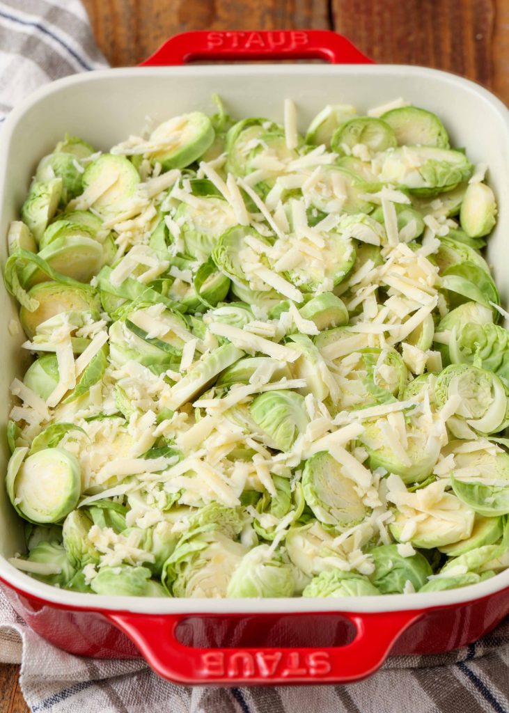 thinly sliced Brussels topped with shredded cheese in baking dish