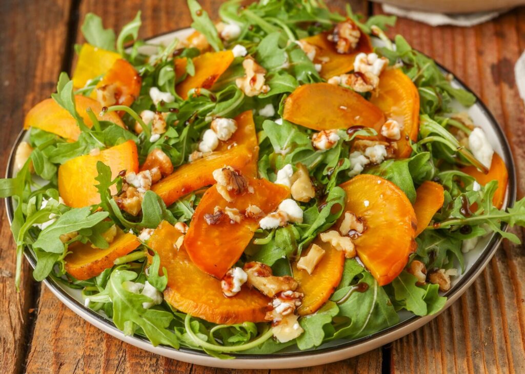 arugula salad on plate with gold beets, walnuts, and goat cheese