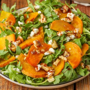 arugula salad on plate with gold beets, walnuts, and goat cheese