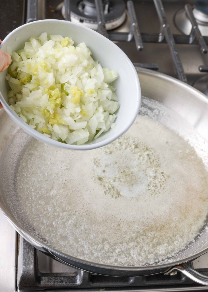 onion, garlic, and celery being added to butter in skillet