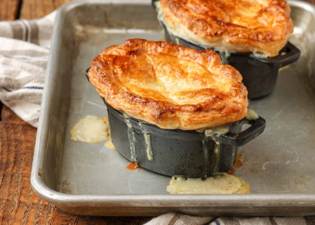 pot pies on baking tray on wooden table with plaid towel
