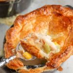 spoon dipping through pastry crust of pot pie