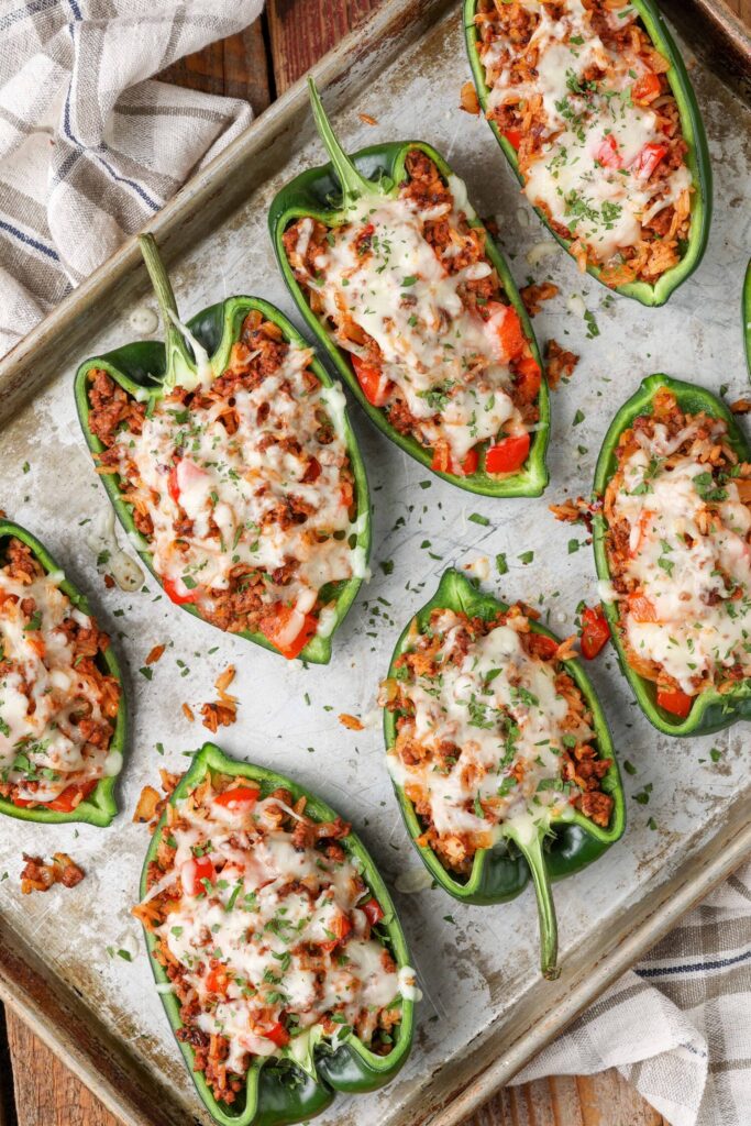 ground beef stuffed peppers topped with cheese on metal pan