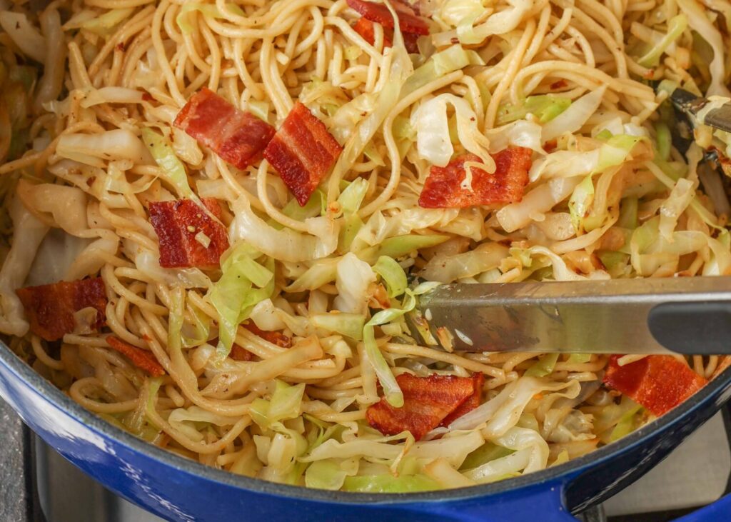 a horizontally aligned photo of a cabbage spaghetti in a blue pot.