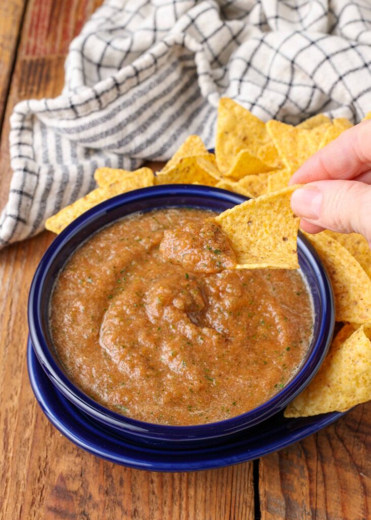 a vertically aligned close up photo of a chip that has been dipped in this easy salsa