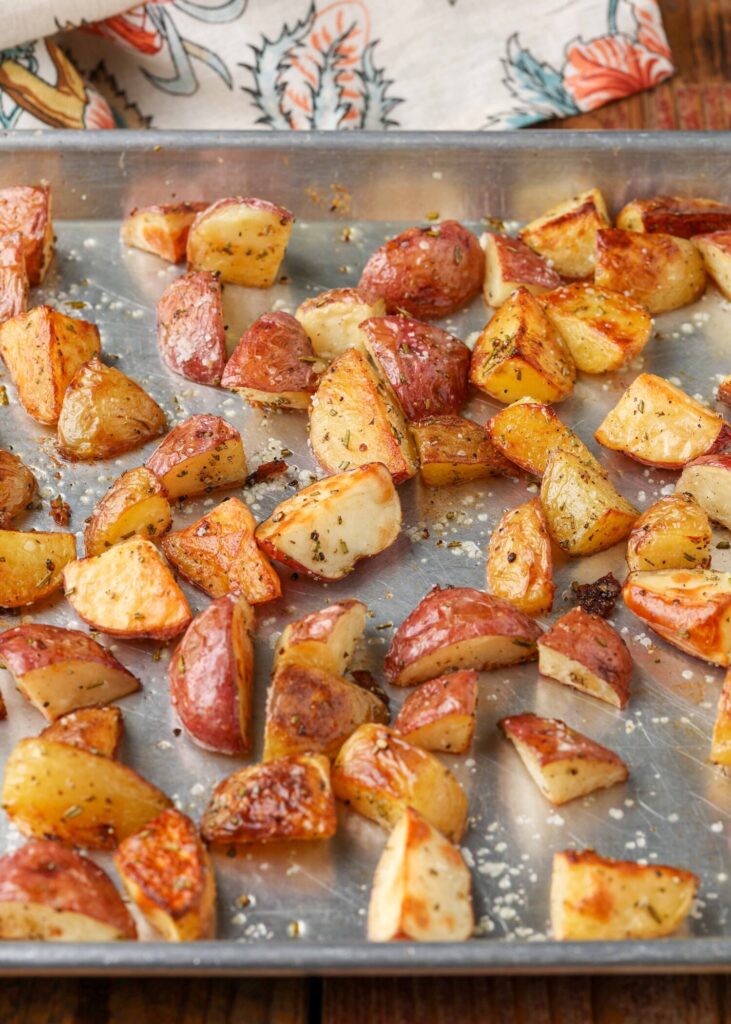 A vertically aligned image of roasted red potatoes on a metal sheetpan.