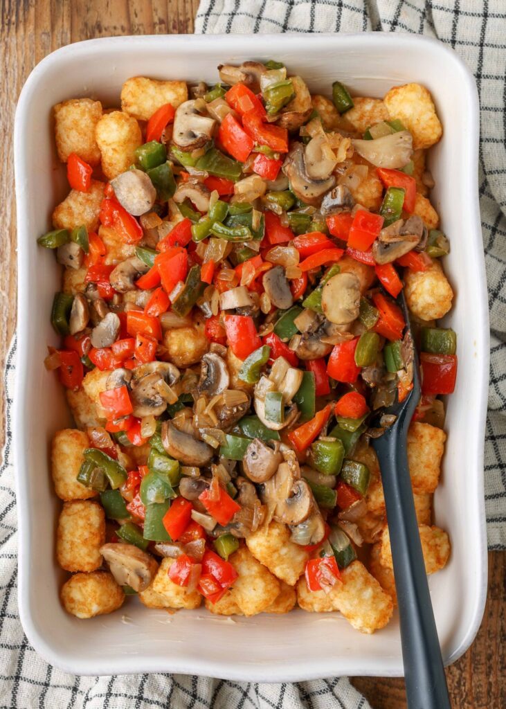 colorful peppers have been placed atop the layer of tater tots in this photo.