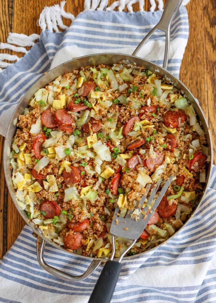 cabbage, rice, and sausage in large skillet with blue towel