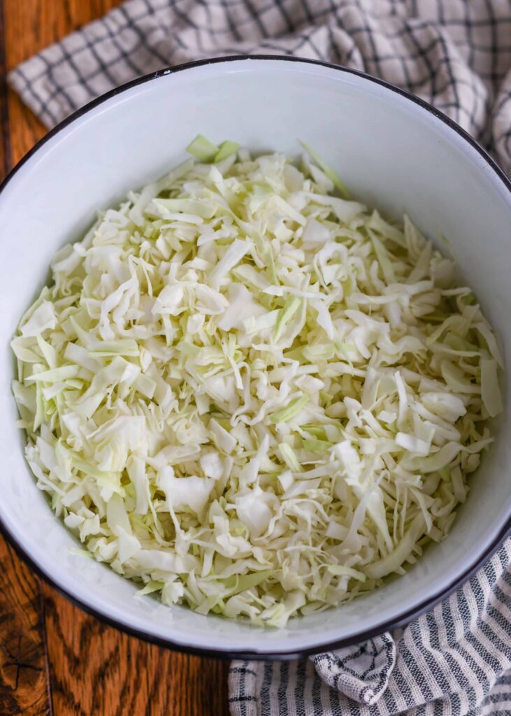 A large white bowl with a blue rim, full of shredded cabbage.